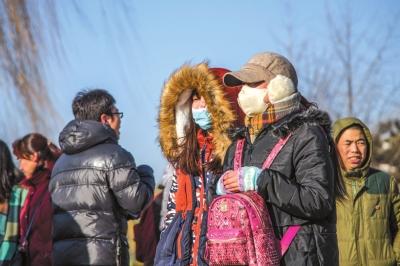 1月18日,北京寒潮来袭,气温突破-10℃,游人在大风中全副武装游览